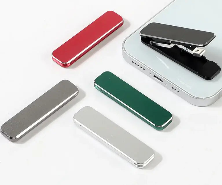 Assorted colors of portable phone stands in red, green, silver, and black on a white background, showcasing sleek design and versatility.